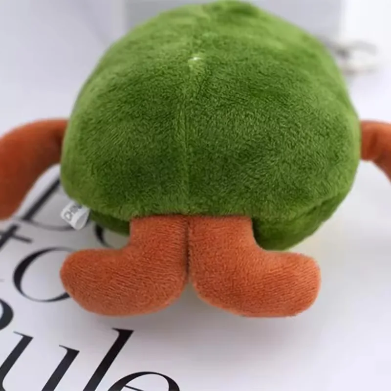 Back view of avocado plush keychain showing rounded green rear body and brown plush feet