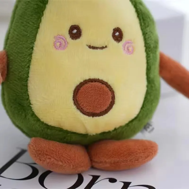 Front view of avocado plush keychain with smiling embroidered face, seed applique, and brown feet