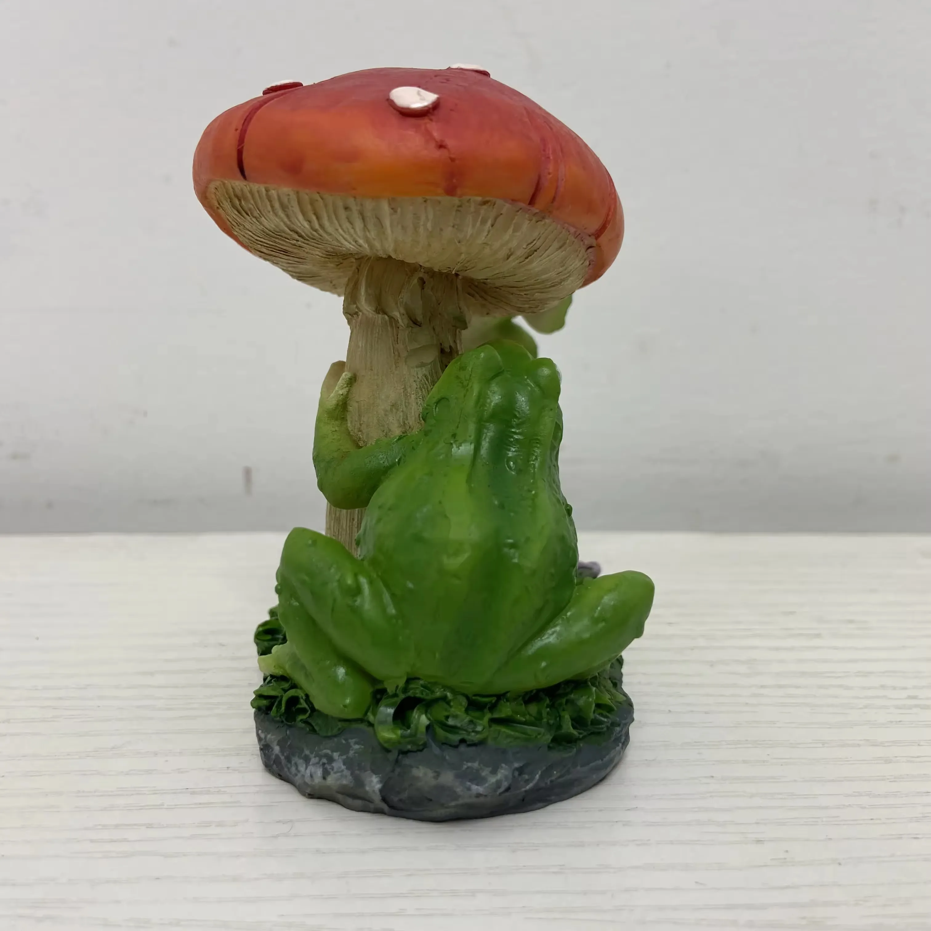 Back view of a resin frog mushroom ornament showing full stem texture and garden base detail