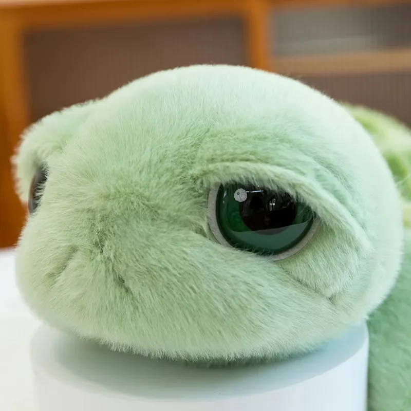 Close-up of the big eyes turtle plush face with mint-green fur and a dark green glossy eye
