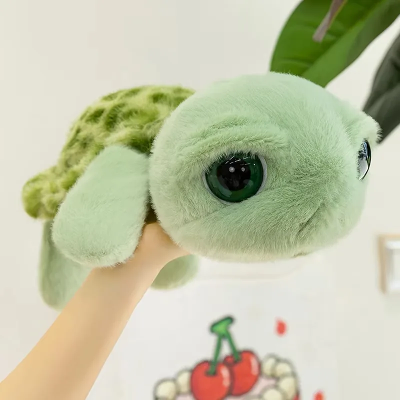 Big eyes turtle plush doll held in one hand to show size and rounded sea turtle shape