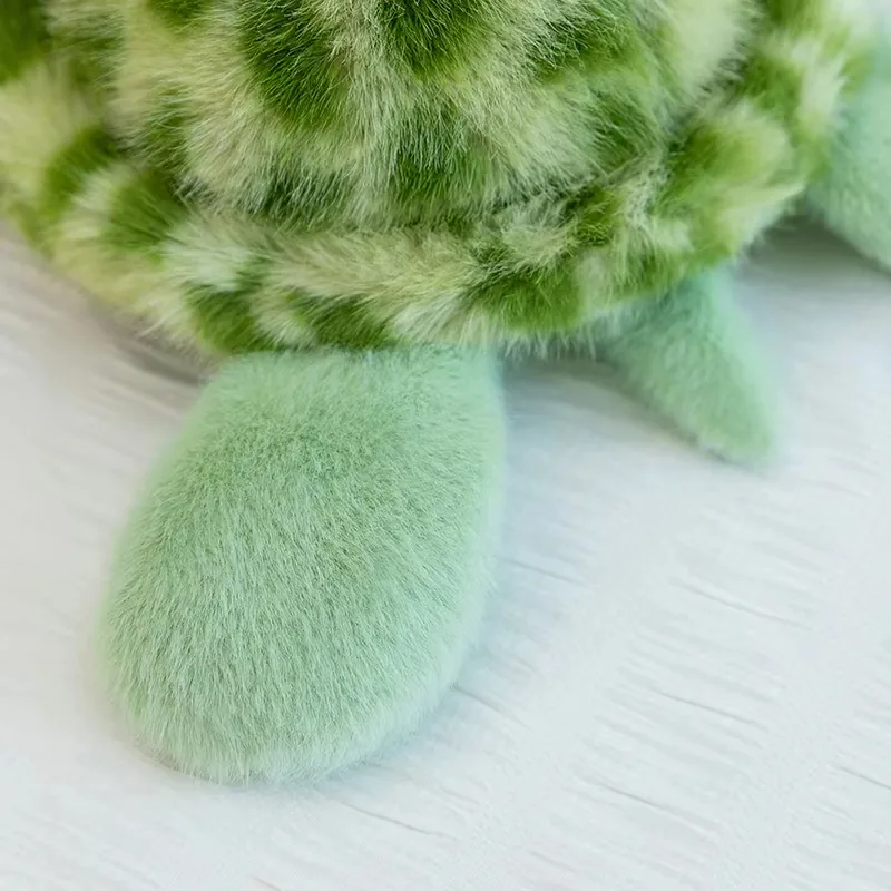 Rounded mint-green turtle plush flipper detail near the shell edge