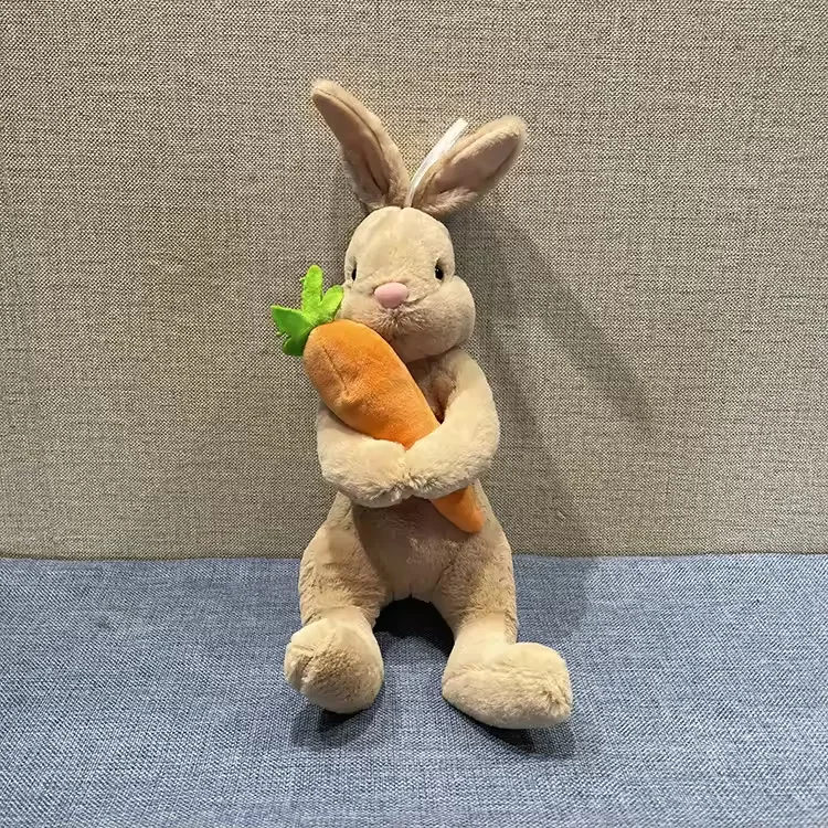Beige rabbit plush doll hugging an oversized carrot with upright long ears