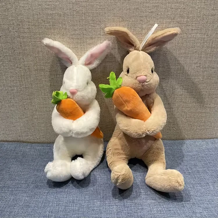 White and beige rabbit plush dolls sitting upright while holding carrots against their chests