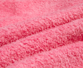 Pink coral fleece close-up showing a fluffy, cozy texture with a blanket-like feel