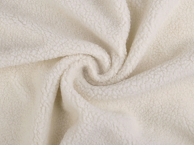 Cream sherpa fabric swirled into a spiral to show its curly fleece texture