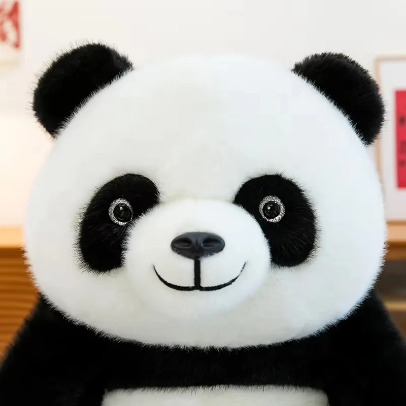 Close-up of panda plush face with black eye patches, rounded muzzle, and smiling embroidery