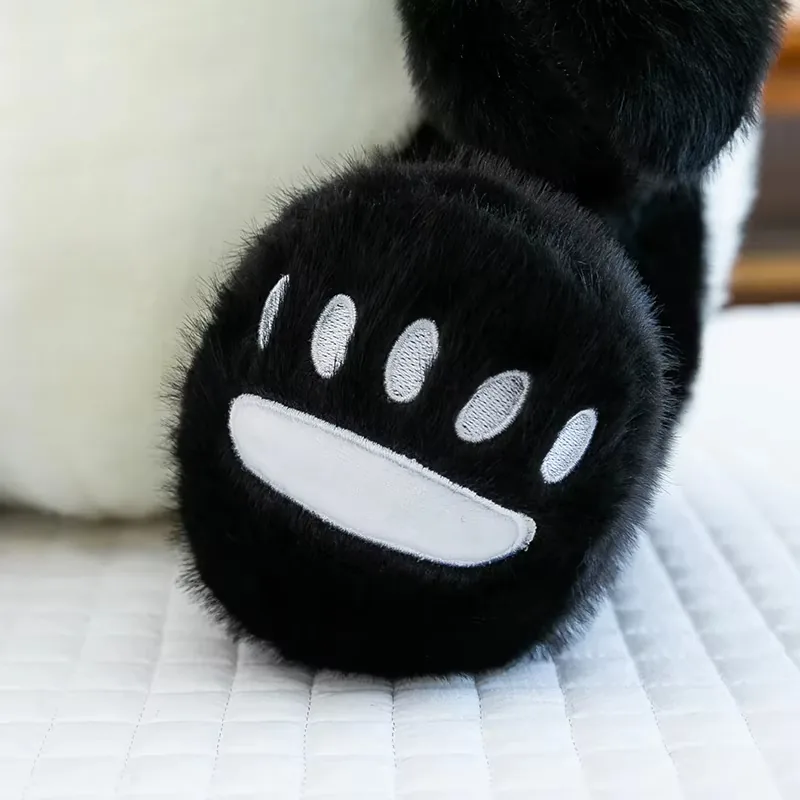 Close-up of black panda plush paw with white embroidered paw pad details