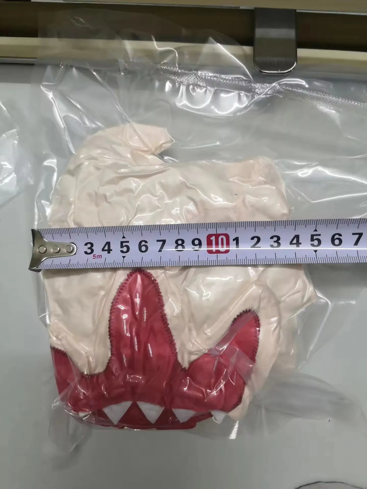 Vacuum-packed beige monster plush shown next to a ruler to indicate compact packed size