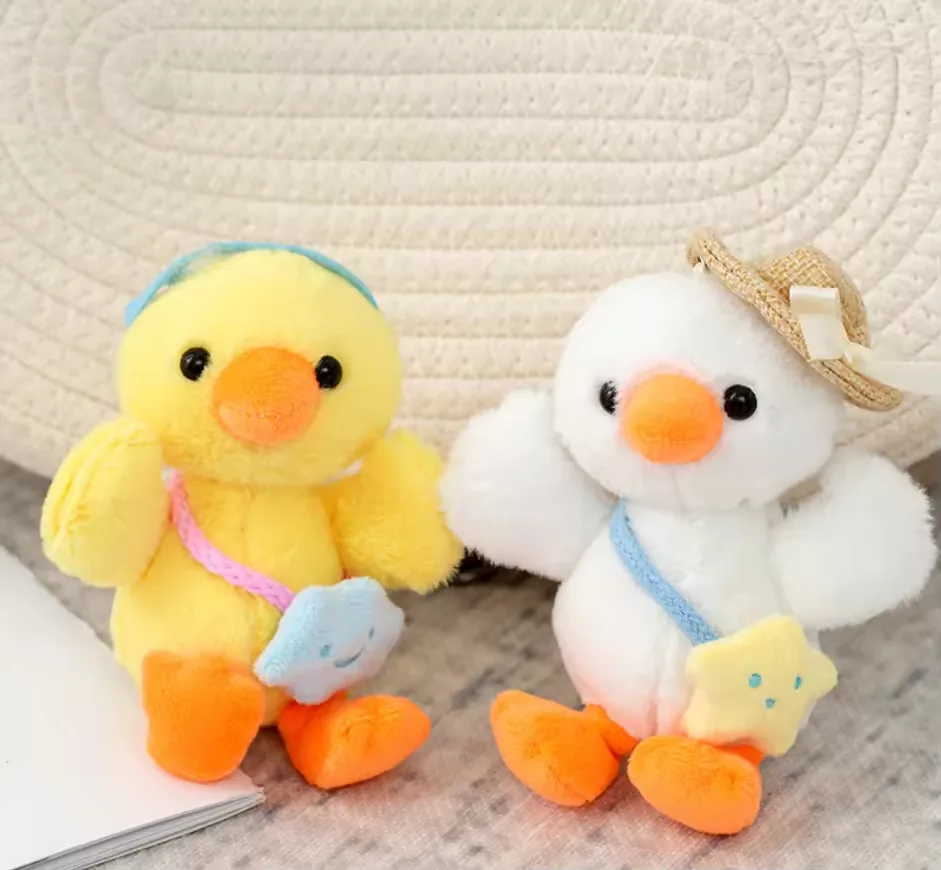 Yellow and white duck backpack charm plush dolls displayed side by side with mini accessories and hanging loops