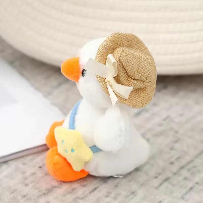 Side detail of the white duck plush charm showing a straw-style hat with ribbon bow