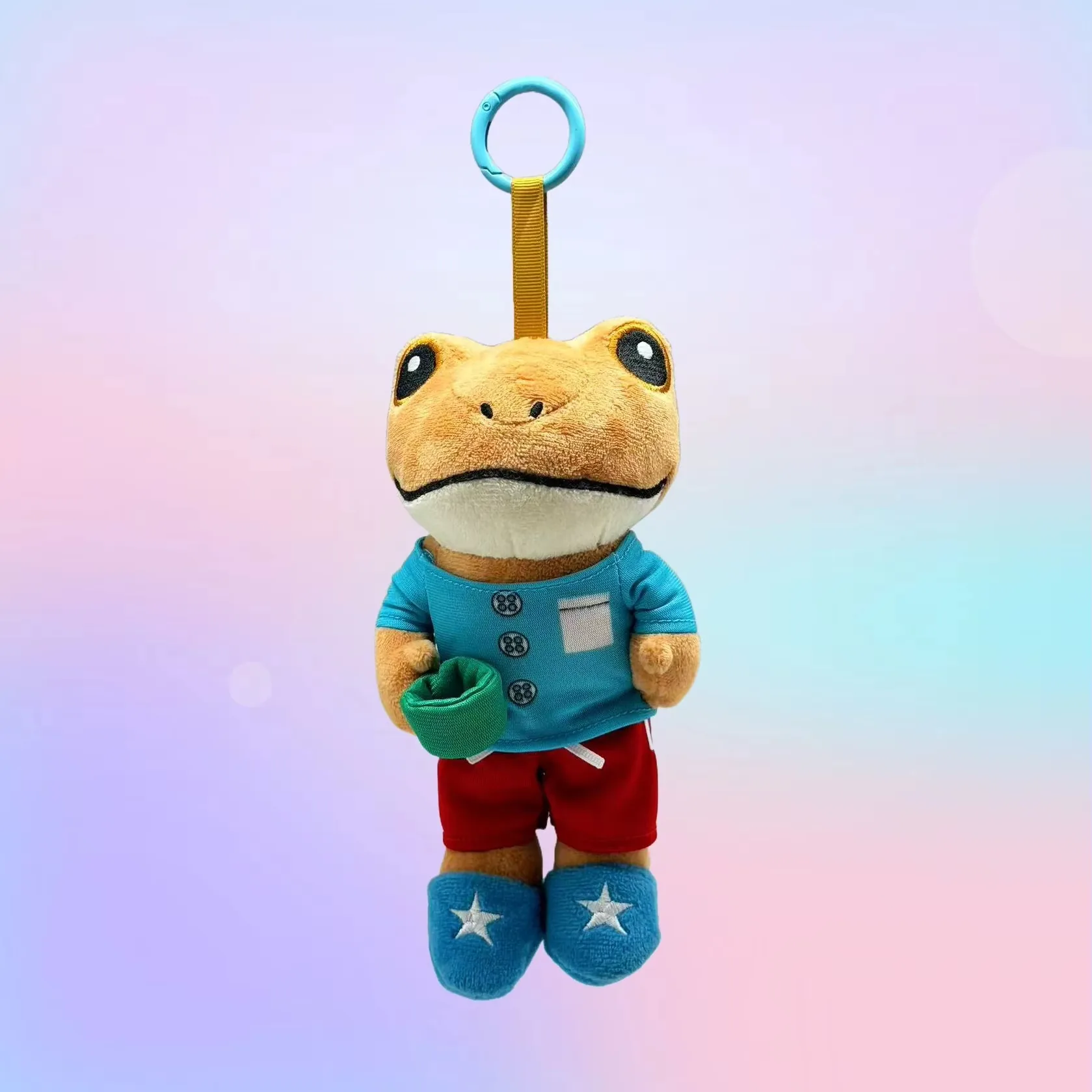 Frog plush keychain wearing a blue shirt, red shorts, and blue shoes with star details