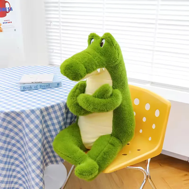 Green crocodile plush doll seated on a yellow chair with crossed arms and a cream belly panel