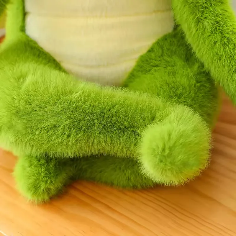 Close-up of the green crocodile plush crossed legs and cream belly panel in the seated pose