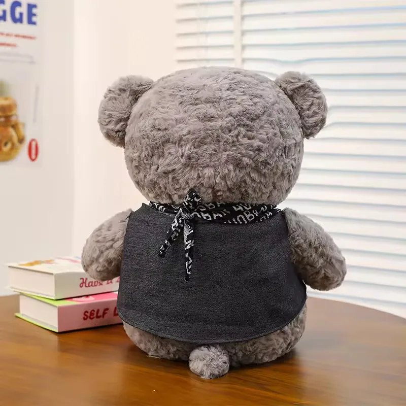 Back view of grey teddy bear plush doll showing scarf tie, vest coverage, and small tail detail