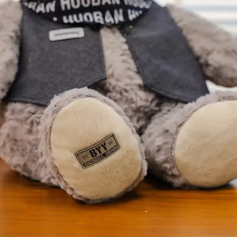 Close-up of grey teddy bear plush paw pad with cream fabric insert and stitched patch detail