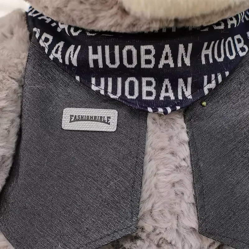 Close-up of grey teddy bear plush scarf and dark vest detail with boutique-style trim