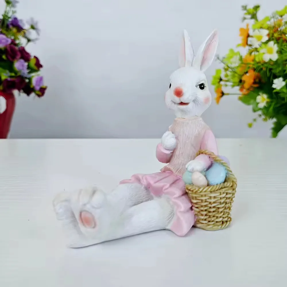 Hand-painted resin rabbit in a pink dress seated beside a basket of pastel eggs for Easter shelf and gift displays