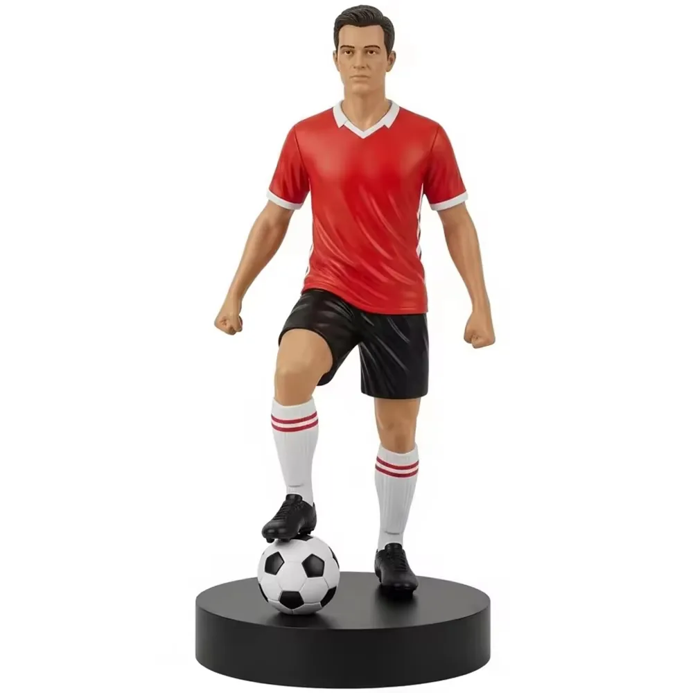 Resin football star commemorative sculpture in a red kit with black shorts and one foot on a football