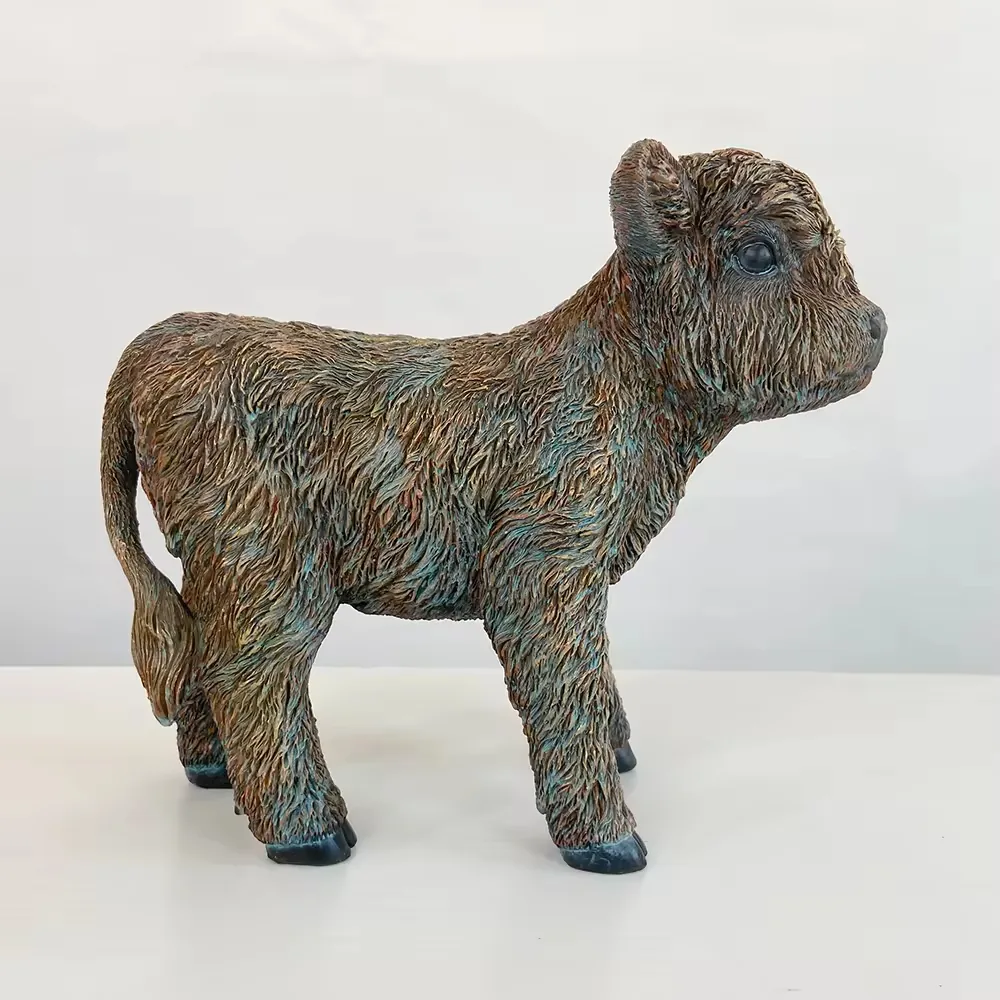 Small resin Highland cow calf figurine with soft facial styling and textured coat shown in profile