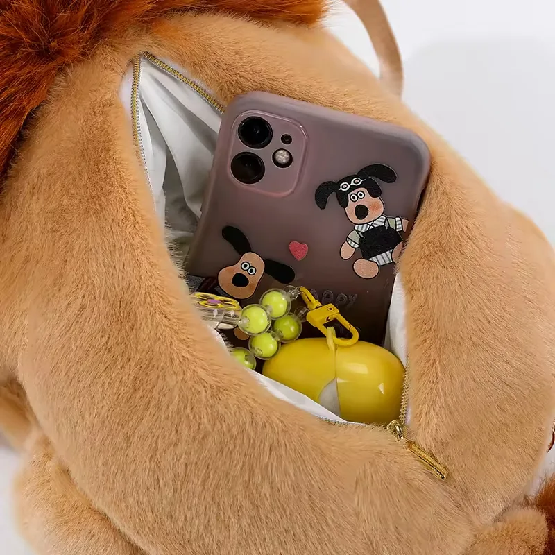 Open storage compartment inside the lion plush backpack bag holding a phone and small daily accessories