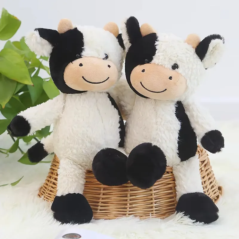 Close-up pair of milk cow plush dolls with shaggy white fur, patchwork faces, and smiling embroidered mouths