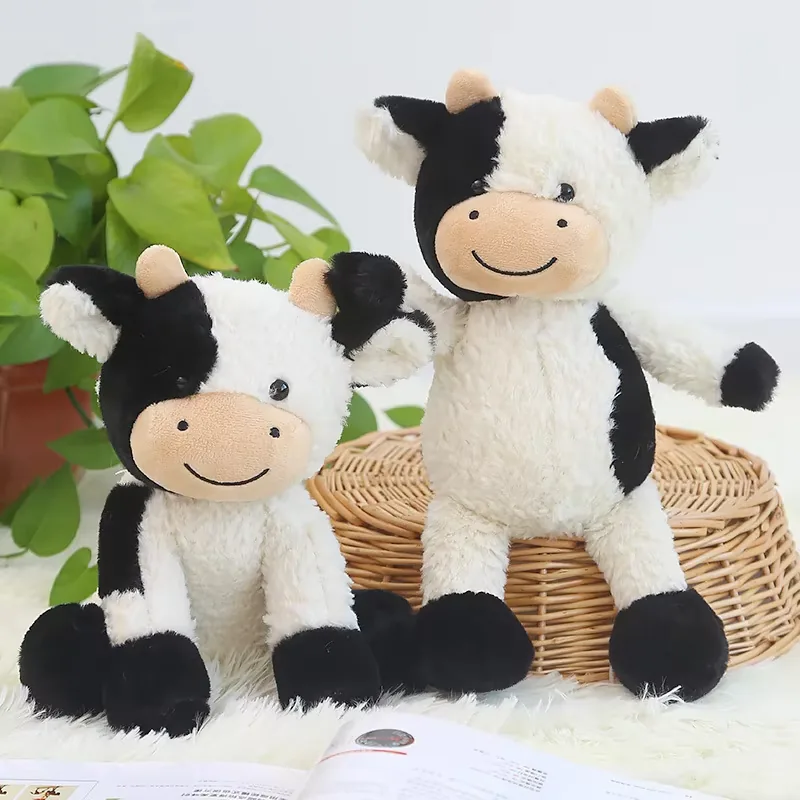 Two milk cow plush dolls displayed side by side in seated poses for farm-animal gift merchandising