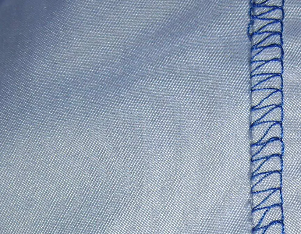 Close-up of an overlock seam with blue thread on light fabric
