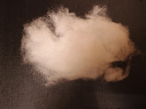 Loose white polyester fiberfill sample spread on a dark surface