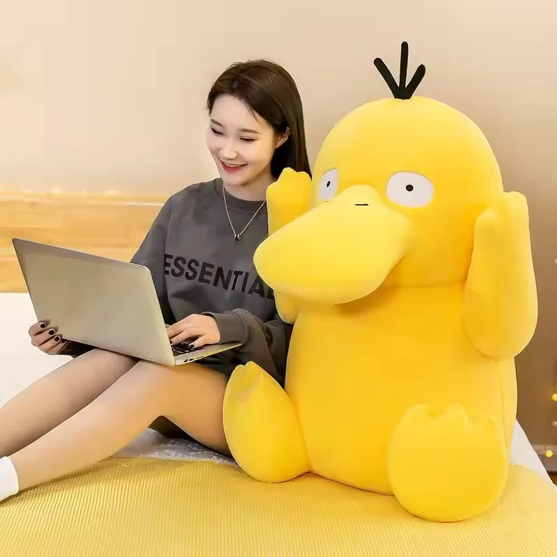 Large Psyduck plush doll beside a model in a lifestyle room scene