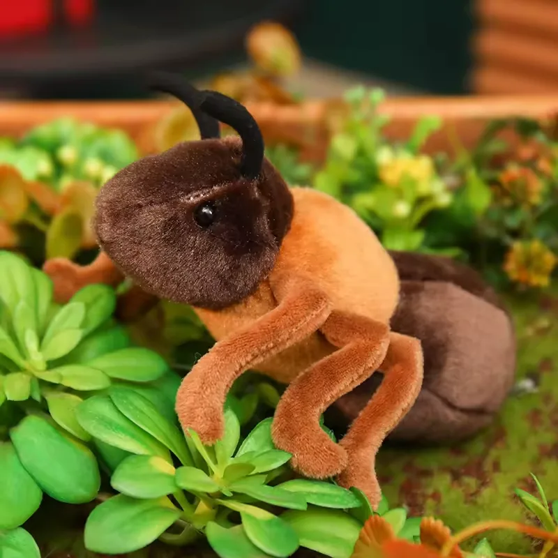 Realistic ant plush toy posed among green plants with raised head and soft crawling legs