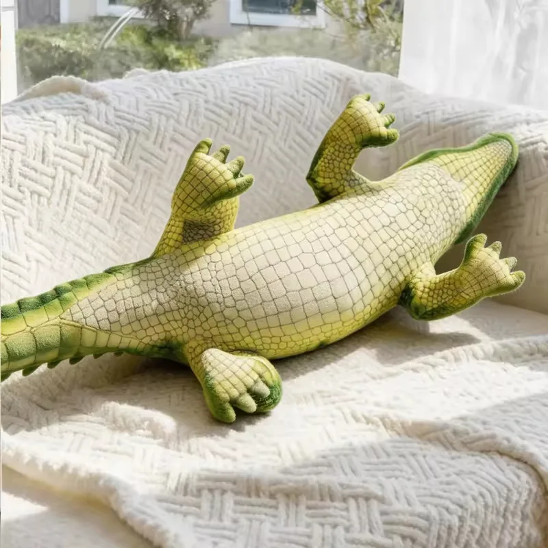 Underside view of a realistic crocodile plush doll showing the soft cream belly, four legs, and long filled body