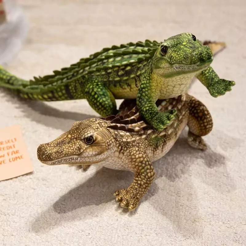 Green and tan realistic crocodile plush dolls stacked together to compare body scale, ridge height, and snout shape