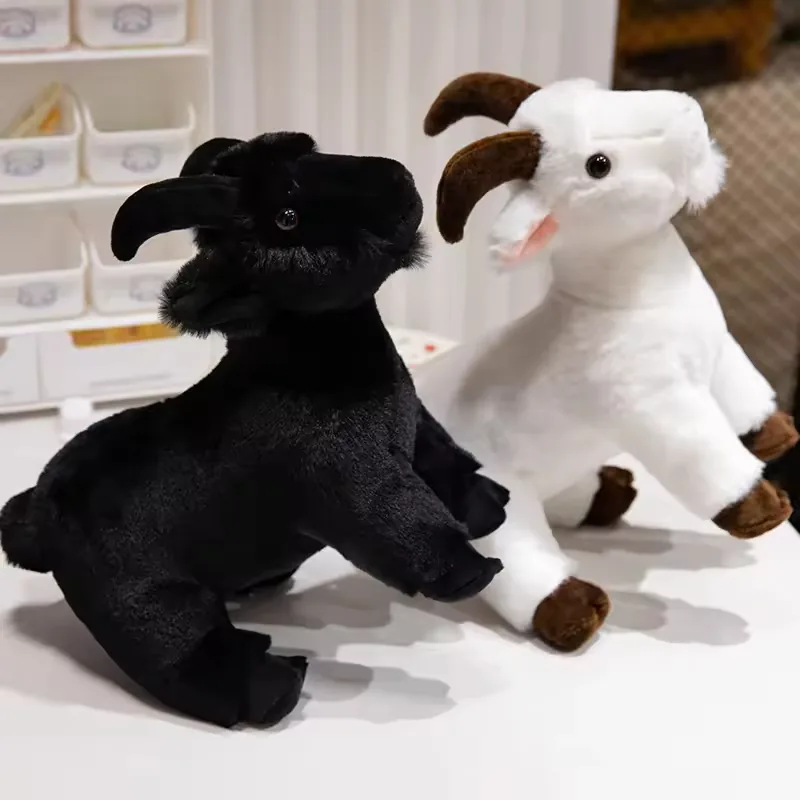 Black and white realistic goat plush toys posed side by side on a tabletop with curved horns and compact standing legs