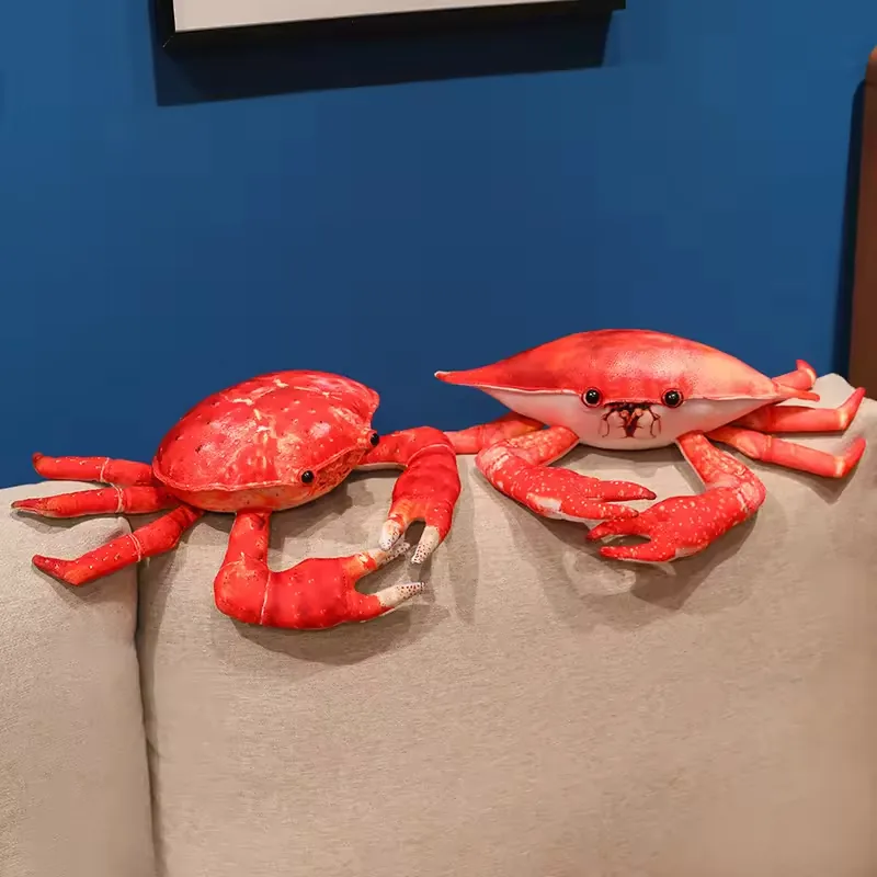 Two plush crab toys in different shell styles displayed side by side on a sofa back