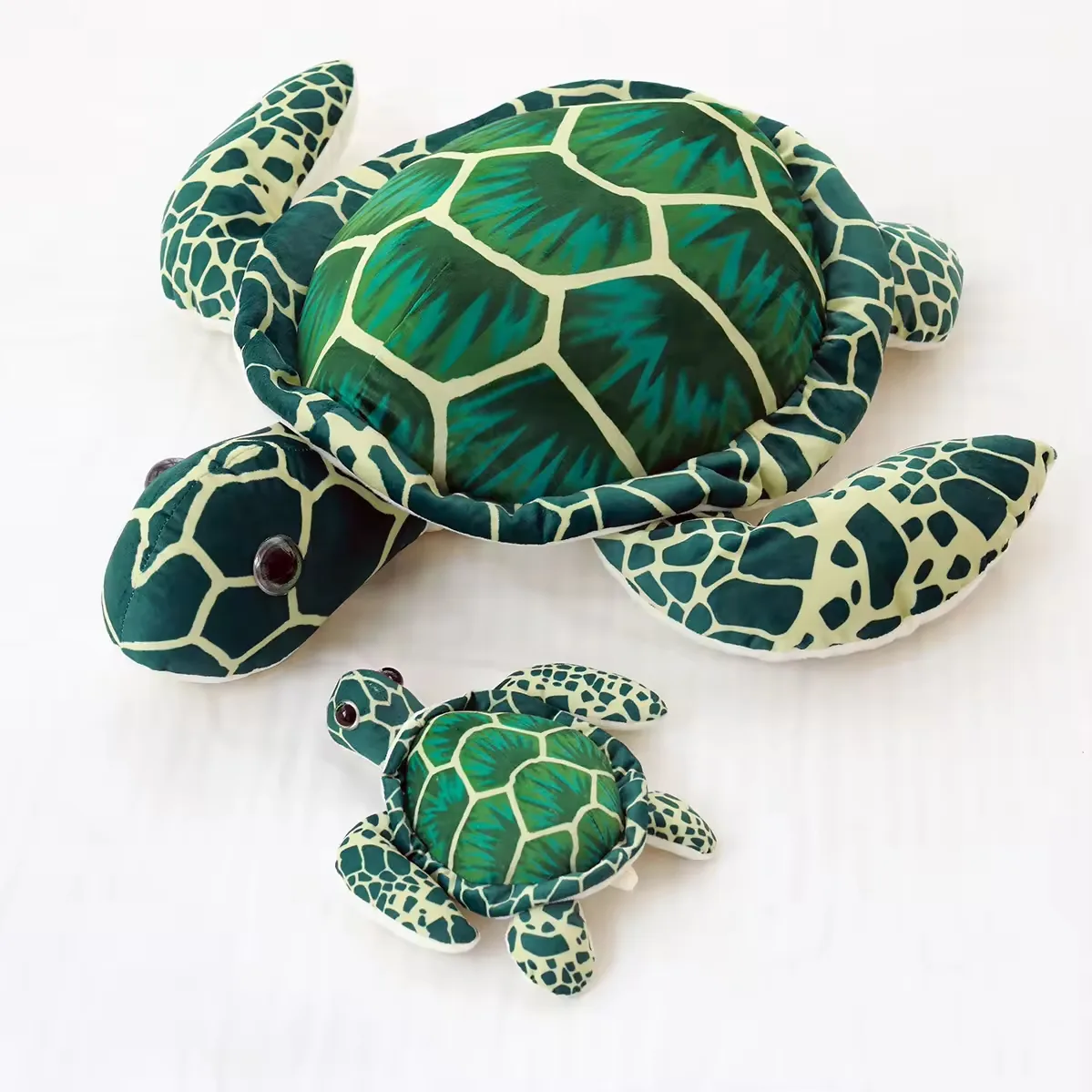 Large and small realistic sea turtle plush pillows shown together in green shell print to compare size and marine-animal shape