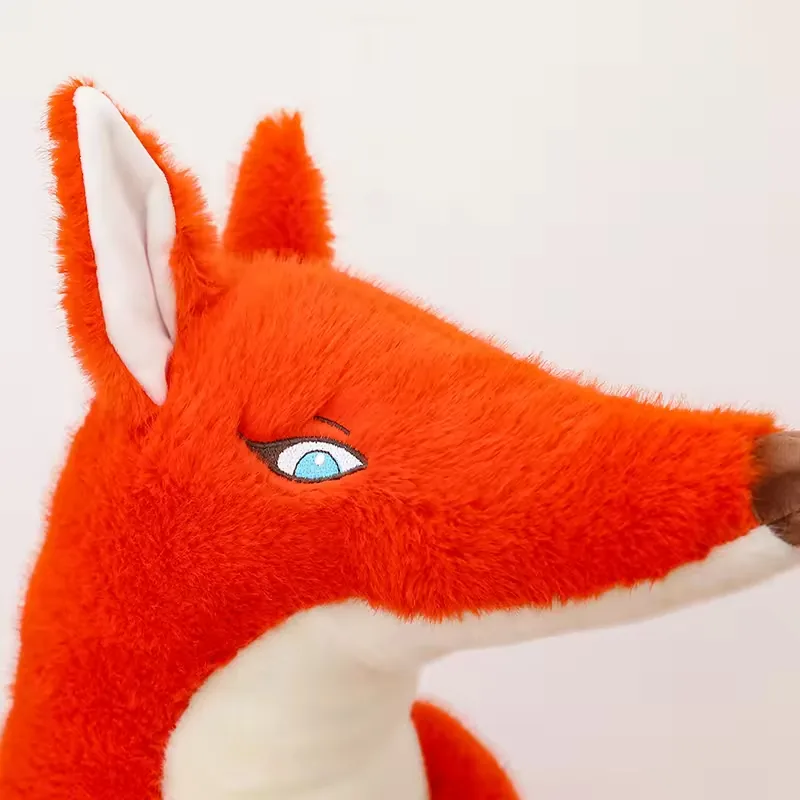 Close-up of the red fox plush face with blue embroidered eye, upright ear, and pointed brown nose
