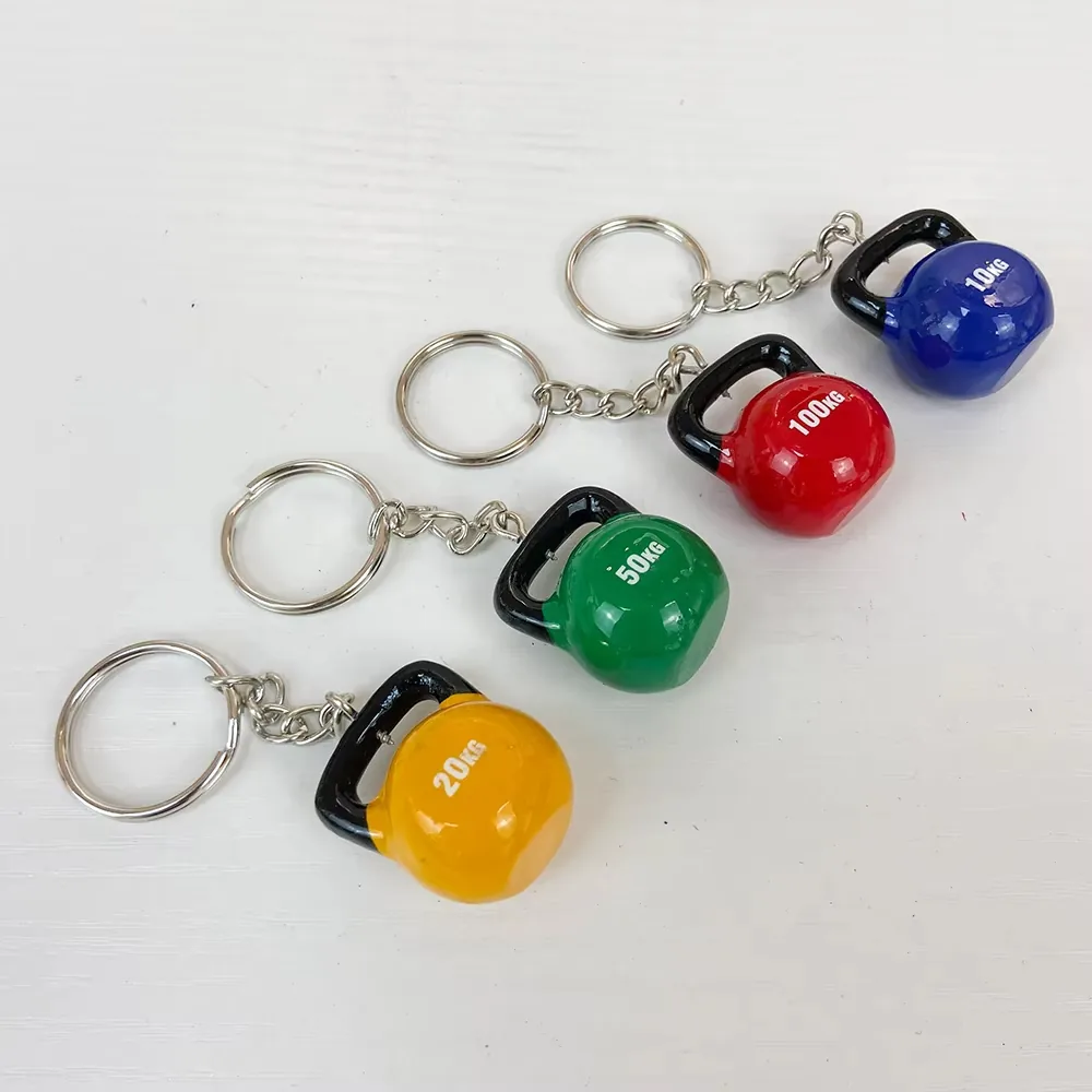 Four kettlebell resin fitness keychains in yellow, green, red, and blue shown as a gym-merch assortment with split rings