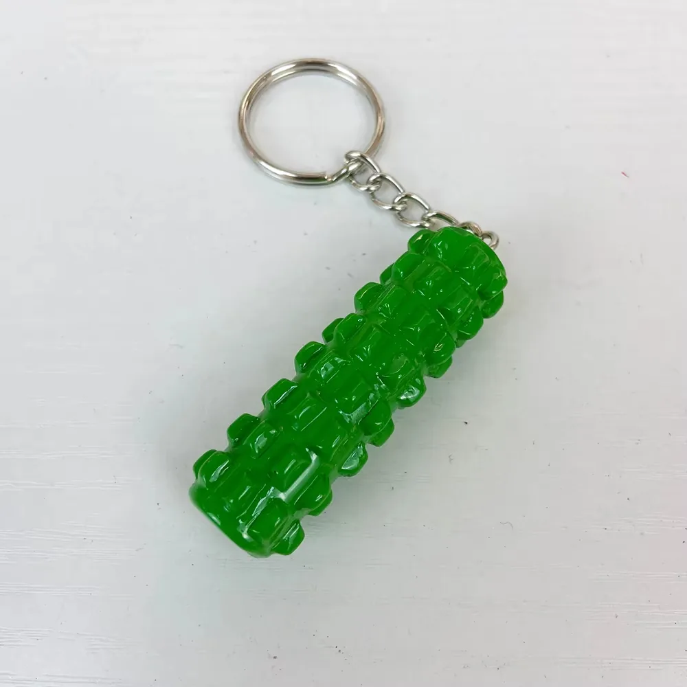 Angled view of a green foam roller resin keychain with raised massage texture