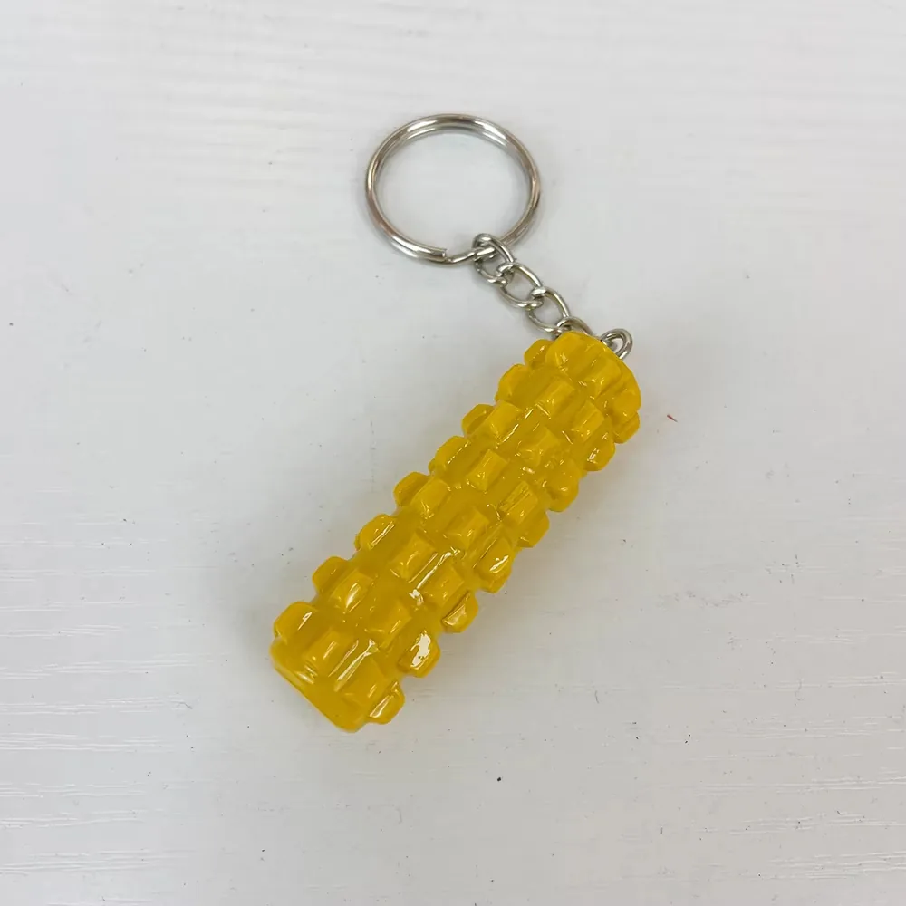 Angled view of a yellow foam roller resin keychain with glossy textured surface