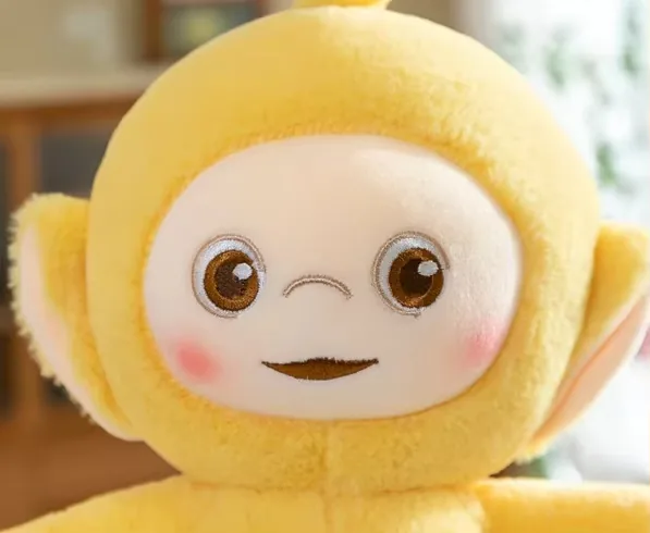 Close-up of the yellow Teletubbies plush doll face with embroidered eyes, blush cheeks, and a calm smile