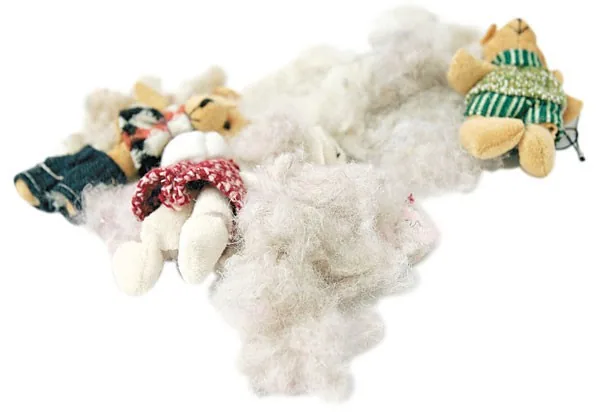 Loose mixed stuffing pulled from old plush toys, showing dull color and uneven texture
