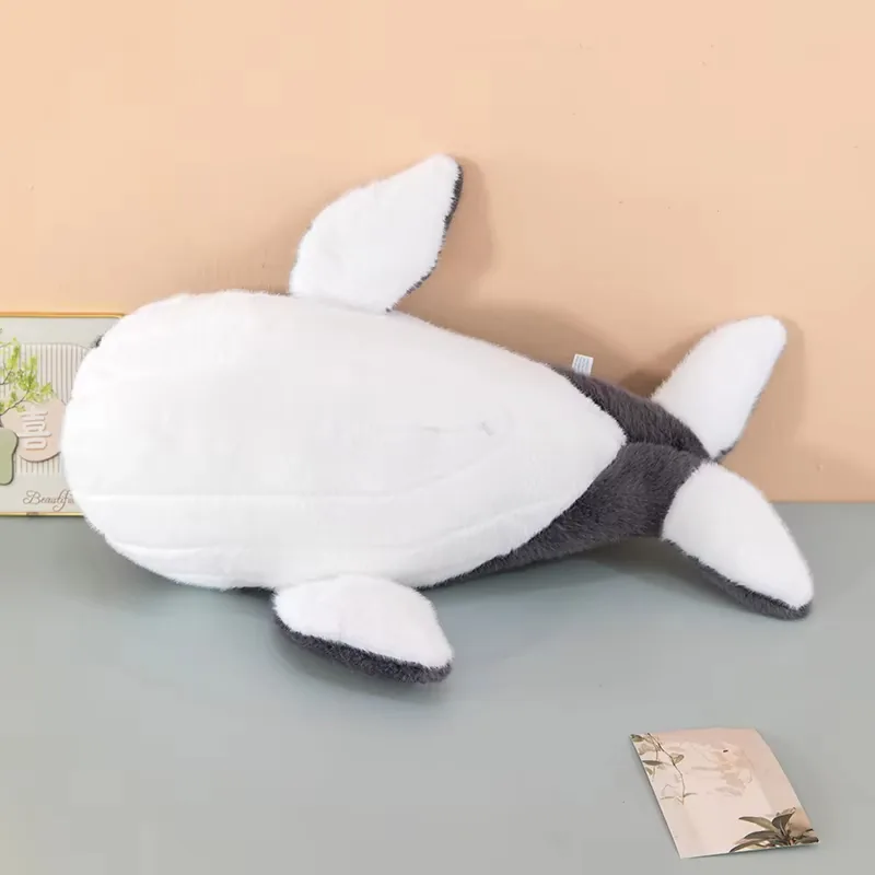 Underside view of the whale plush pillow showing the full white belly panel and white fin undersides