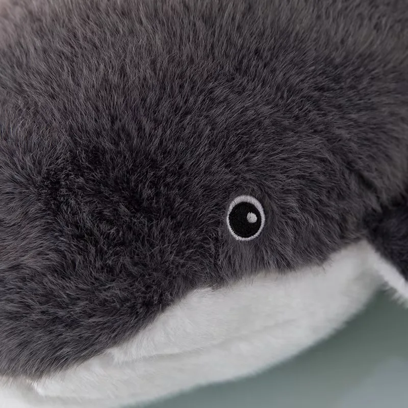 Close-up of the whale plush pillow eye embroidery set into soft grey fur