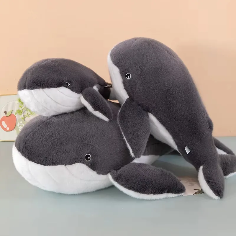 Three whale plush pillows stacked together with rounded heads and soft side fins