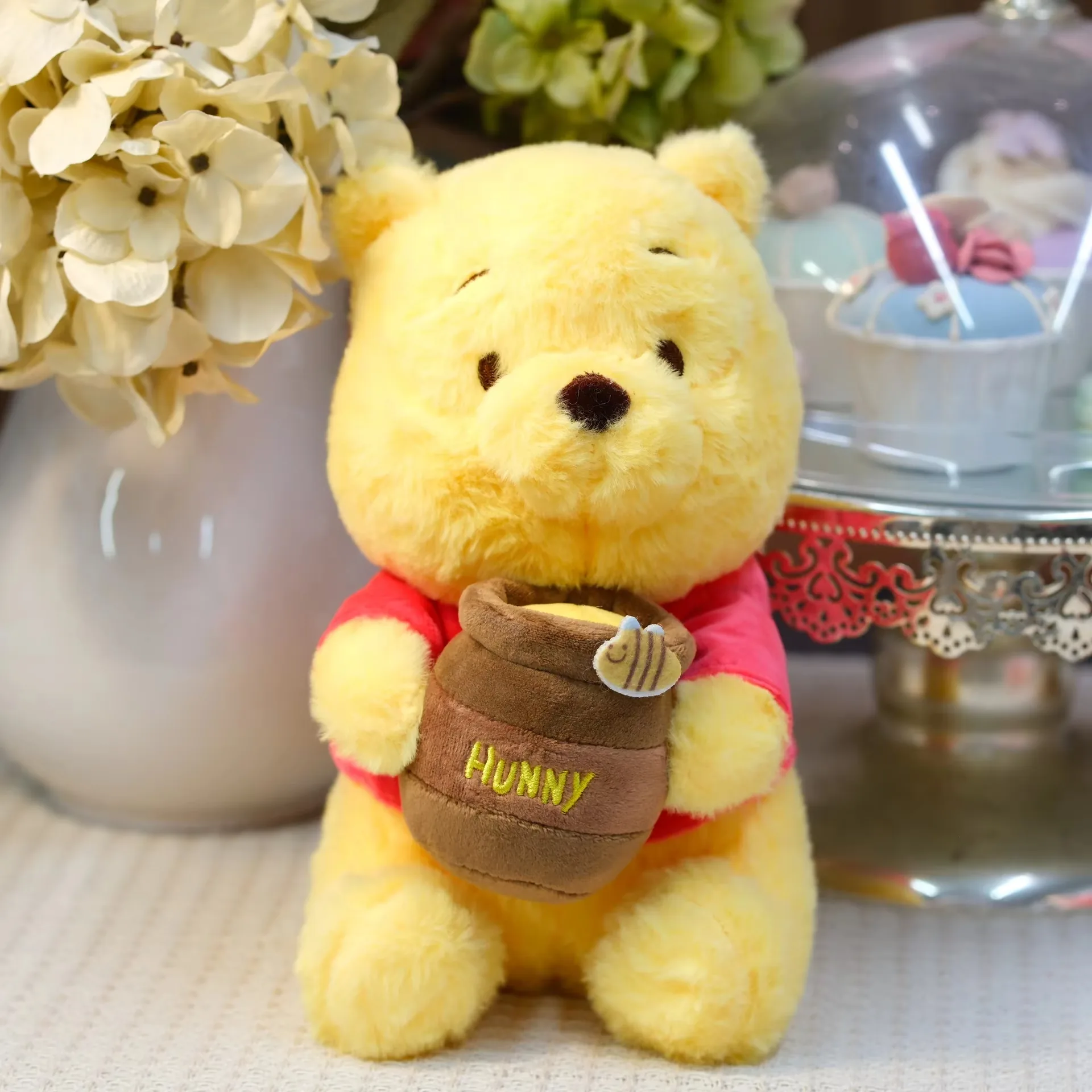 Yellow honey jar bear plush doll in a red shirt holding a brown hunny pot