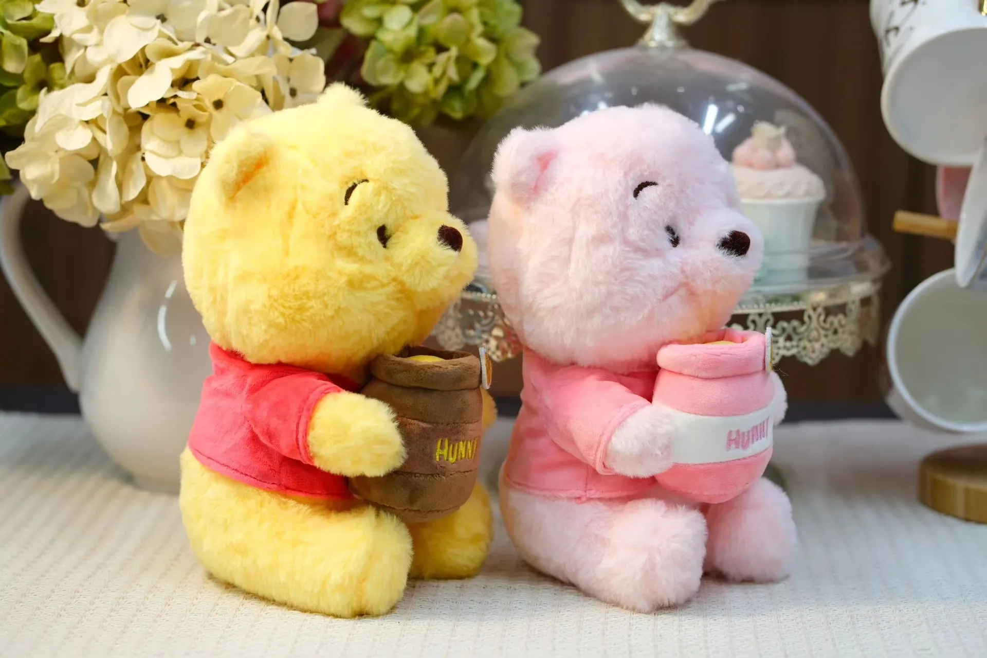 Three-quarter view of yellow and pink honey jar bear plush dolls showing the honey pot angle